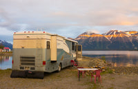 RV with portable water storage at lake during sunset